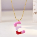 Macro detail of gold chain necklace featuring pink and purple enamel letter E pendant - Letter E