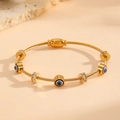 Detailed macro of gold braided cuff bracelet featuring blue evil eye charms and crystals - Evil Eye Paved Style (R711)