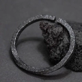 Minimalist dark grey hammered Mobius ring for men displayed on a natural dark rock - SZ133-Wuteng Black Bracelet