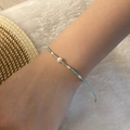 Detail of hand-woven beaded bracelet with pearls and adjustable cord on a wrist - Blue