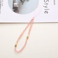 Pink beaded phone charm with crystal stones and golden clover detail on a desk - K989 Clover Style / K989 Pink Crystal Phone Chain / Pink