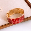 Macro shot of vintage red and gold enamel square link bracelet with spiral pattern detail - Gold Red