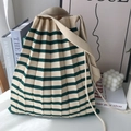 Dettaglio della borsa a pieghe in maglia a righe beige e verde su tavolo bianco - Righe Verdi e Beige