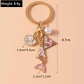Detail of golden mermaid keychain with shell charms, pearl, and dimension measurements - Pink