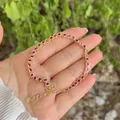 Bracciale placcato oro 18K con zirconi rossi tondi tenuto a mano su uno sfondo naturale - Pietra Rotonda Rossa (3)