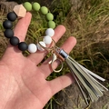 Close-up of silicone beaded keychain with wooden bead, golden ring and leather tassel - Green