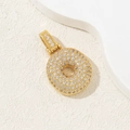 Gold plated letter pendant with zircon stones on a cream textured background - Letter O