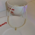 Detailed macro view of a 14K gold plated pearl necklace with a round gold pendant charm - 20# White Pearl Gold Ball Necklace