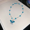 Macro del ciondolo a farfalla blu con strass e perle bianche sulla catena lucida - Collana Farfalla Blu