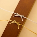 Elegant gold and silver bow snake chain necklaces displayed on luxury wooden blocks - Gold Necklace