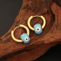Detail of golden stainless steel evil eye hoop earrings with blue enamel on wood base - Light Blue