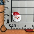 Macro view of a 1cm mini resin Santa Claus charm on a measuring scale for nail art - Santa Claus