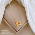Detail der goldenen Schleifen-Halskette mit Maßen 1,4x1,1 cm auf beigem Display-Pad - Gold