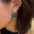 Close-up of a green agate stone charm on a gold hoop earring and ear cuff on a model - Malay Jade