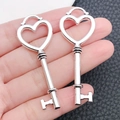 Detailed view of silver heart-shaped key charms with ornate crown and hollow patterns - Heart Key Pendant (5873)
