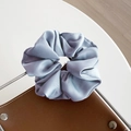 Large light blue satin scrunchie with silky folds placed on a minimalist desk - Light Blue