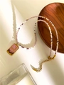 Macro view of a gold pendant with crescent moon and stars on a colorful beaded necklace - Pink Square Plate
