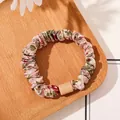 Detail of floral pink satin scrunchie with rectangular accent on light wood tray - Satin Floral Pink