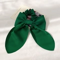 Close-up of elegant green satin bow hair scrunchie with long ribbons on white fabric - Green