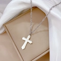 Primer plano de collar con cruz de acero de titanio plateado sobre seda blanca - Plateado
