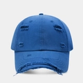 Detailed close-up of distressed ripped edges on a vintage navy blue cotton baseball cap - Blue