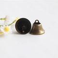 Close-up of two bronze vintage metal bells with hanging rings and internal clappers - 32mm
