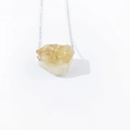 Macro shot of irregular natural raw citrine quartz stone pendant on a silver thin chain - Citrine
