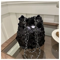 Elegante borsa a secchiello con paillettes nere e tracolla a catena su un tavolo - Nero
