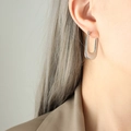 Pendientes geométricos en U plateados con textura de rayas verticales usados por una modelo - Color Acero