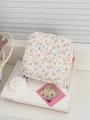 Quilted floral makeup bag with pink zipper on decorative book in a soft-lit aesthetic setting - Zipper Style