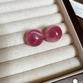 Vista macro de pendientes redondos de piedra ojo de gato rosa en joyero de madera - Rosa