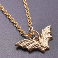 Macro shot of 18K gold bat pendant featuring fine metal texture and sleek link chain - Gold Color + Necklace Chain