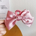 Handheld view of a pink satin bow hair claw clip with elegant fabric texture details - Satin Bow Claw Clip / Peach Blossom Pink