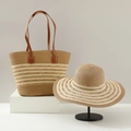 Detail of straw tote bag and sun hat set with white wavy trim on minimalist pedestals - Braid Khaki Mixed
