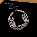 Collier ras du cou en strass argenté avec design en maille creuse sur fond noir - Style Maille Argentée