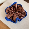 Nahaufnahme eines braunen Samt-Haargummis mit blauer Spitzenkante auf Holzoberfläche - Blauer Spitzenbesatz Kontraststil / Kaffeebraun