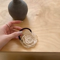 Close-up of beige fabric flower hair tie with black elastic band on wooden surface - Withered Rose Hair Tie-Off-White