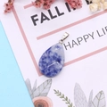 Macro detail of faceted teardrop natural stone pendant with silver clasp and blue texture - Blue Spot Stone