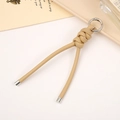 Detail of beige braided PU leather keychain with silver ring on a minimalist tray - Khaki