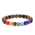 Natural lava stone chakra bracelet with tiger eye beads and copper charm on white background - Tiger Eye 7 Chakra