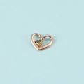 Pendentif cœur en or rose avec cristal vert olive sur fond bleu clair en gros plan - Or Rose Août
