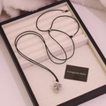 Vue détaillée du pendentif pomme de pin argenté sur cordon noir dans un coffret cadeau - Argenté