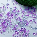 Bunte irisierende Glasperlen in verschiedenen Größen für Nagelkunst auf weißem Stoff - Eisiges Lila