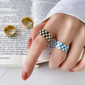 Detail bunter Emaille-Ringe mit Karomuster auf Goldbändern, an der Hand getragen - US 6 / Blau und Weiß Schachbrett