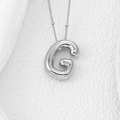 Macro detail of silver G balloon pendant with polished metallic luster on white texture - Letter G Pendant