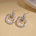 Dettaglio di orecchini a doppio cerchio intrecciati argento con finitura satinata - Stile a Doppia Texture Tonda Smerigliata / Argento