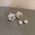 Detailopname van Franse vintage bloemenoorknopjes en pareloorbellen op een donkere ondergrond - Zilveren Pin. Wit Iridiserend