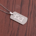 Vue macro d'un collier en acier argenté avec un pendentif rectangulaire à lettre E évidée - Lettre E