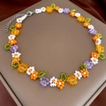 Detail of colorful flower beaded necklace with a silver lobster clasp on a beige tray - Multi-color Flowers/Woven Seed Beads