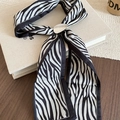 Detail of zebra pattern silk scarf with a silver oval metal ring buckle on a book - Black White Zebra